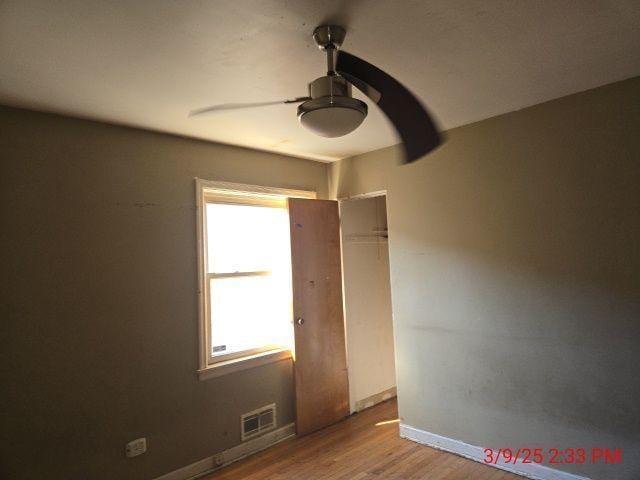 unfurnished room with visible vents, baseboards, ceiling fan, and wood finished floors