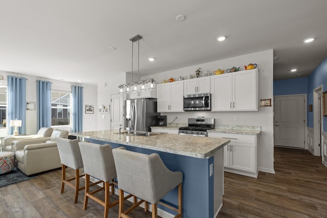 kitchen featuring a sink, light countertops, appliances with stainless steel finishes, a kitchen breakfast bar, and dark wood-style flooring