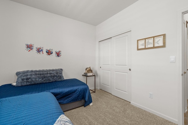 carpeted bedroom featuring baseboards and a closet