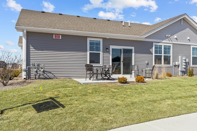 back of house featuring a patio area, a lawn, and a shingled roof