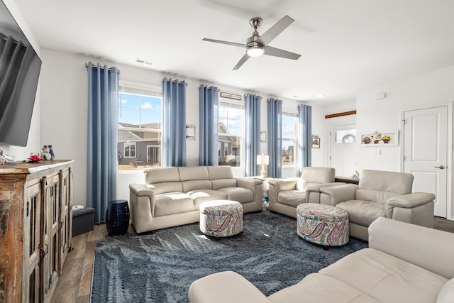 living area with visible vents, a ceiling fan, and wood finished floors