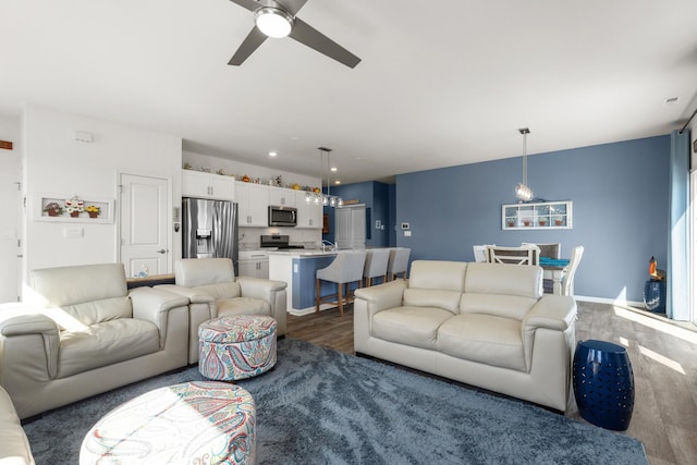 living area featuring baseboards, ceiling fan, and dark wood-style flooring