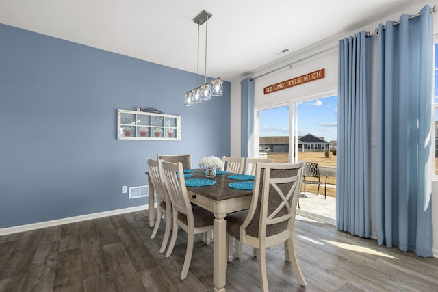 dining area with a chandelier, visible vents, baseboards, and wood finished floors