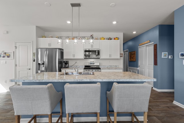 kitchen with a center island with sink, dark wood-style flooring, light countertops, appliances with stainless steel finishes, and white cabinetry