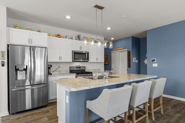 kitchen with a sink, dark wood finished floors, appliances with stainless steel finishes, white cabinets, and light countertops