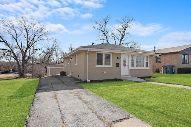 bungalow-style home featuring brick siding, central air condition unit, an outdoor structure, and a front yard