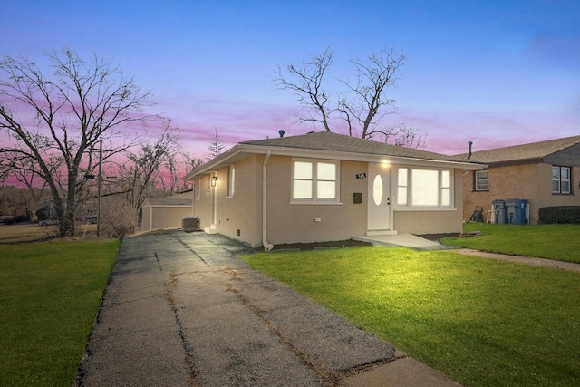 bungalow-style home featuring a front yard, an outbuilding, cooling unit, driveway, and brick siding