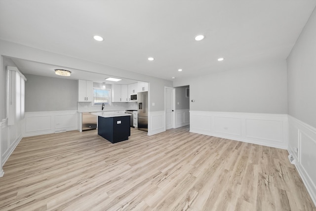 kitchen with light wood-style flooring, a kitchen island, white cabinetry, recessed lighting, and light countertops