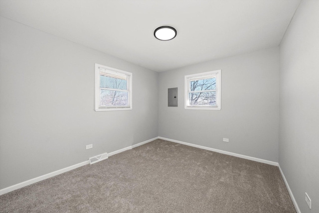 carpeted spare room with electric panel, visible vents, and baseboards