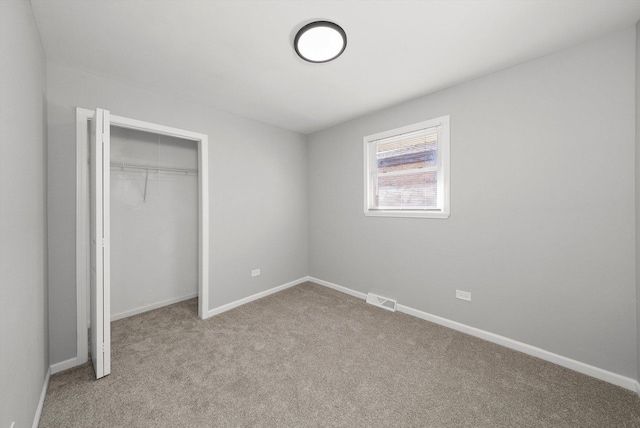 unfurnished bedroom with carpet, visible vents, a closet, and baseboards