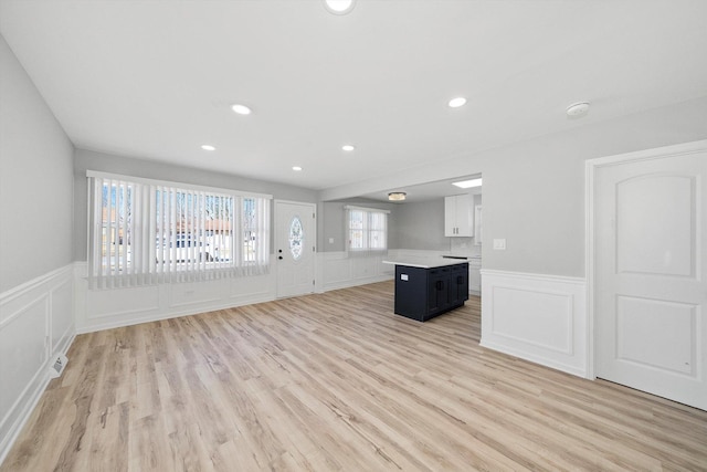 unfurnished living room with recessed lighting, a wainscoted wall, and light wood-style flooring