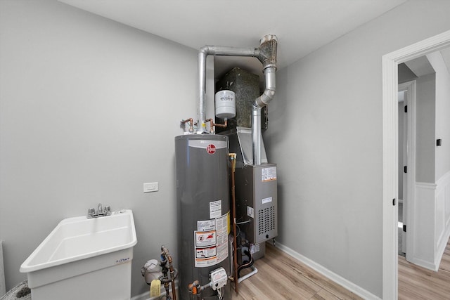 utility room with water heater and a sink