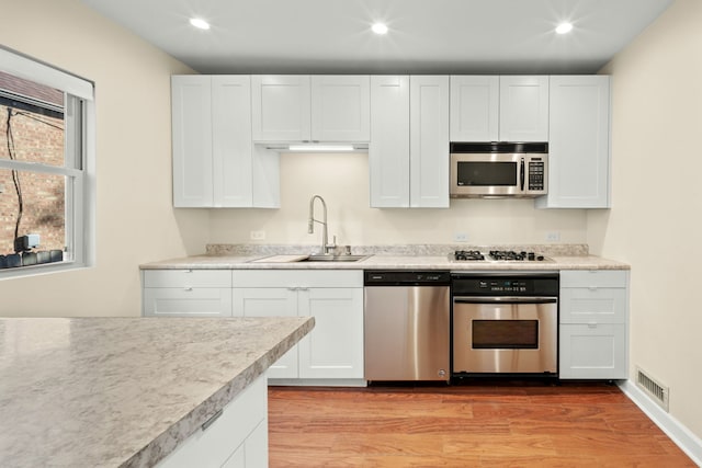 3119 W 83rd St, Chicago, IL 60652 - kitchen with stainless steel appliances, a sink, light wood finished floors, recessed lighting, and white cabinets