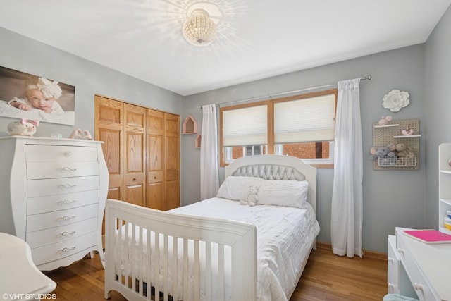 bedroom with wood finished floors, a closet, and baseboards