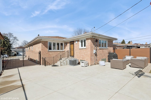 back of house with an outdoor living space, a gate, central AC unit, and brick siding