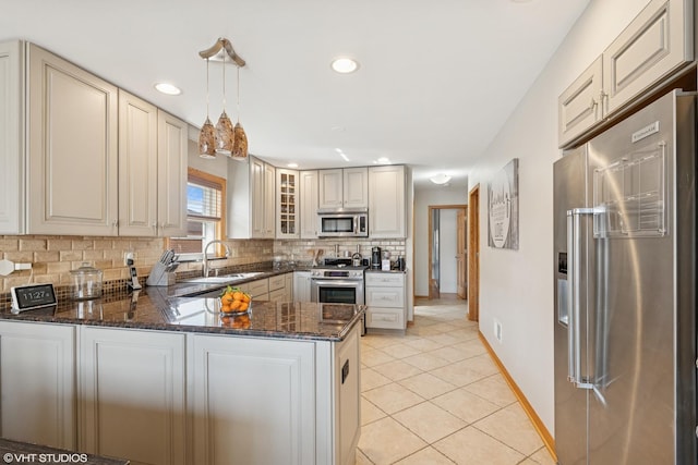 kitchen featuring light tile patterned flooring, a sink, decorative backsplash, cream cabinetry, and appliances with stainless steel finishes