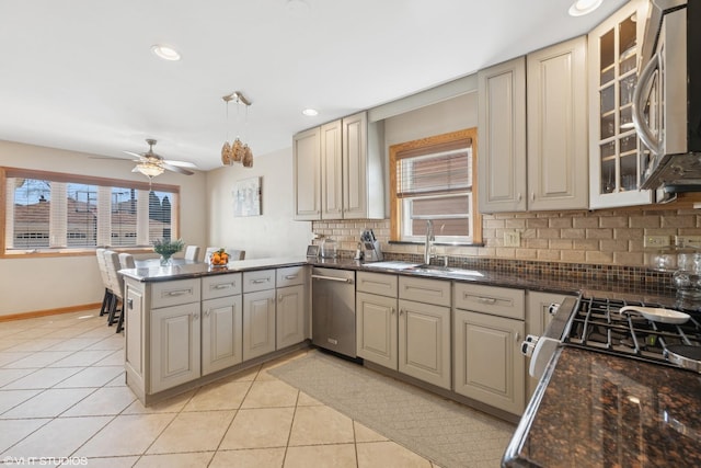 kitchen with a peninsula, light tile patterned flooring, stainless steel appliances, decorative backsplash, and cream cabinets