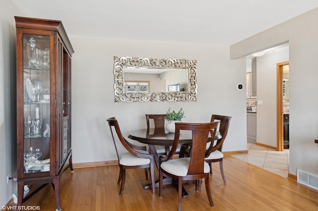 dining room featuring visible vents, baseboards, and light wood-style flooring