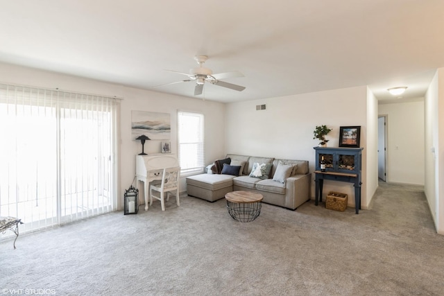 living area featuring visible vents, carpet flooring, and a ceiling fan