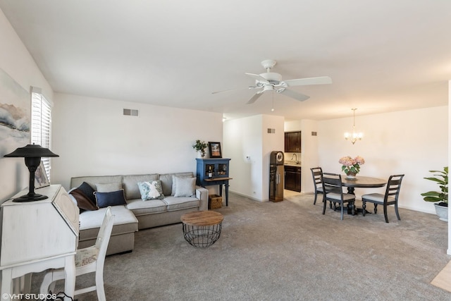 living area featuring visible vents, light colored carpet, and ceiling fan with notable chandelier