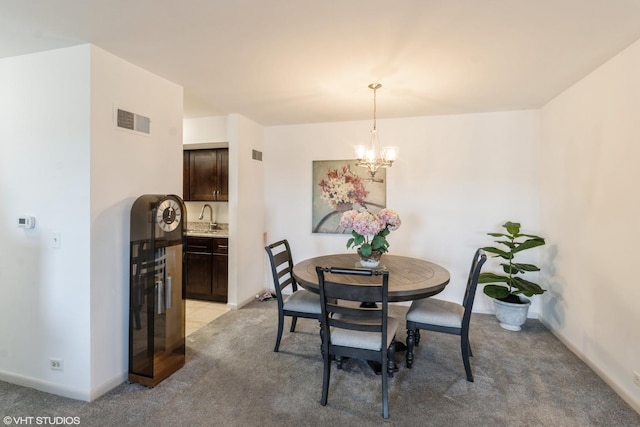dining area with an inviting chandelier, light colored carpet, and visible vents
