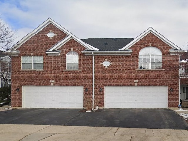 view of front of home featuring aphalt driveway, brick siding, and an attached garage