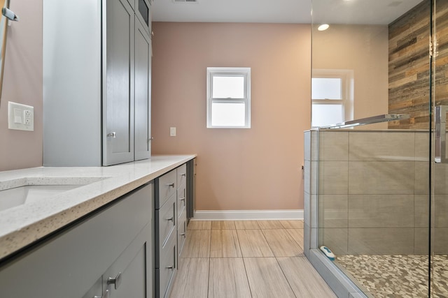 full bath with vanity, visible vents, baseboards, tiled shower, and tile patterned flooring