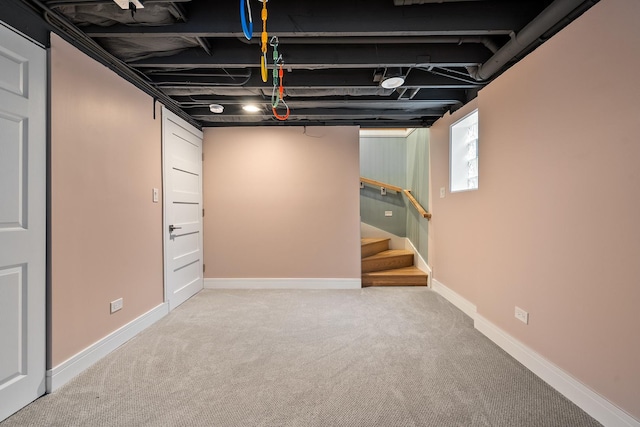 finished below grade area featuring stairway, baseboards, and carpet flooring