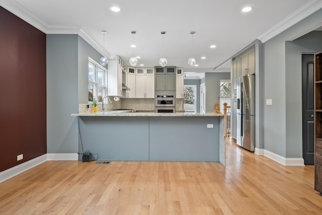 kitchen with light wood-style flooring, a peninsula, stainless steel appliances, and crown molding