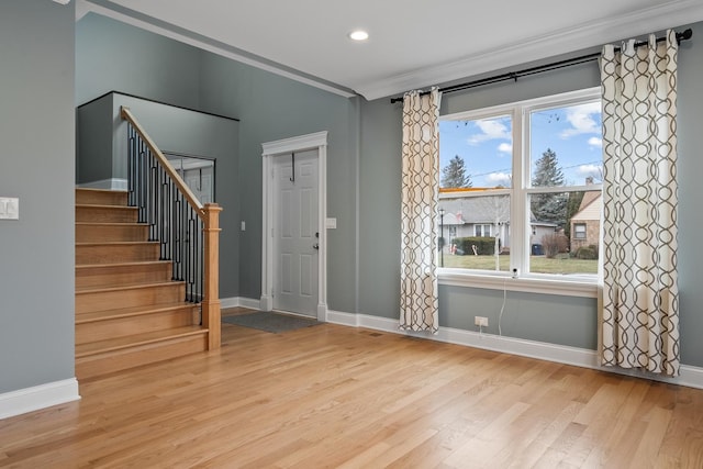 entrance foyer featuring stairway, baseboards, wood finished floors, and crown molding