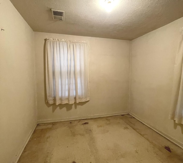 unfurnished room with visible vents and a textured ceiling