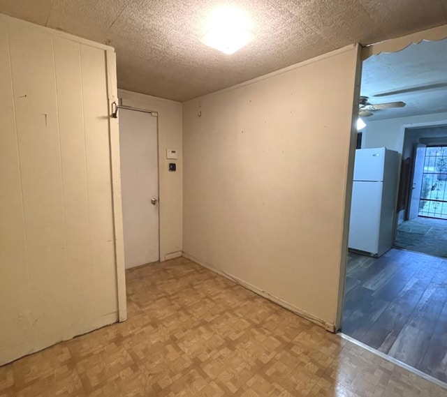 empty room featuring light floors, a textured ceiling, and ceiling fan