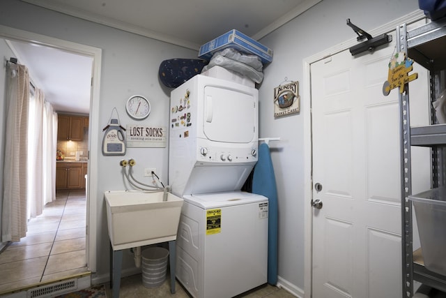 laundry room with visible vents, stacked washer and dryer, crown molding, tile patterned flooring, and laundry area