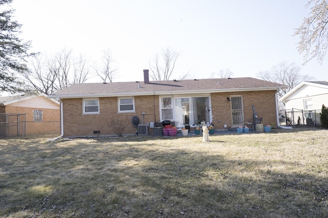 rear view of property with brick siding, fence, central AC unit, a chimney, and a yard