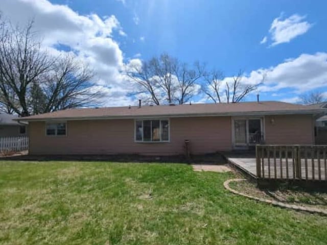 back of property with a lawn and a deck