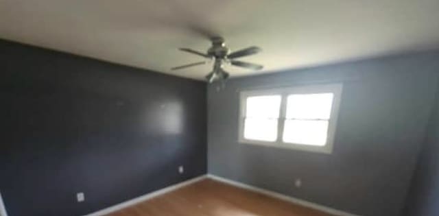 unfurnished room with a ceiling fan, wood finished floors, and baseboards