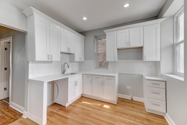 kitchen featuring a sink, a wealth of natural light, light wood-style flooring, and white cabinetry