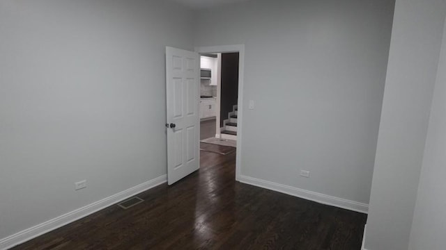 spare room with visible vents, baseboards, and dark wood-style floors