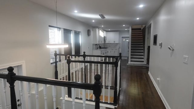 hallway with baseboards, dark wood finished floors, recessed lighting, a sink, and an upstairs landing