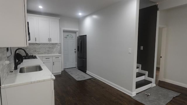 kitchen with decorative backsplash, freestanding refrigerator, dark wood-style floors, white cabinets, and a sink