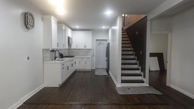 kitchen featuring dark wood finished floors, decorative backsplash, light countertops, and a sink