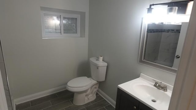 bathroom featuring a shower, baseboards, toilet, and vanity