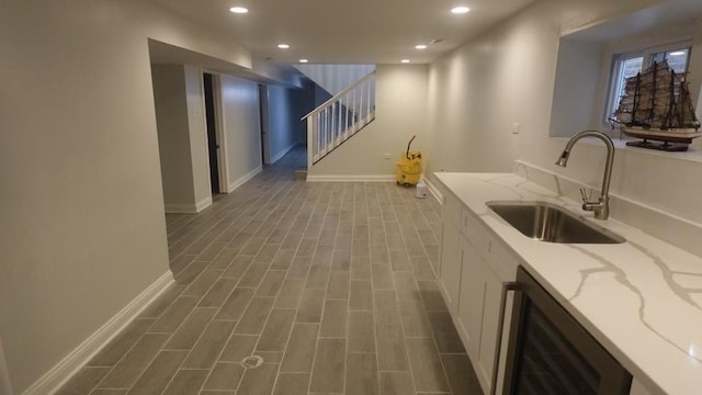 bar with wood finish floors, beverage cooler, a sink, recessed lighting, and stairway