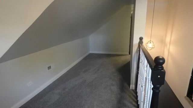 bonus room with baseboards, dark carpet, and vaulted ceiling