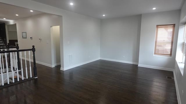 empty room with dark wood-style floors, visible vents, recessed lighting, and baseboards