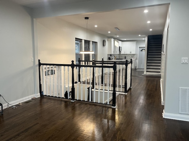 hall featuring dark wood finished floors, recessed lighting, baseboards, and visible vents