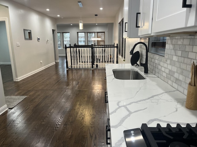 kitchen featuring tasteful backsplash, dark wood finished floors, light stone counters, white cabinets, and a sink