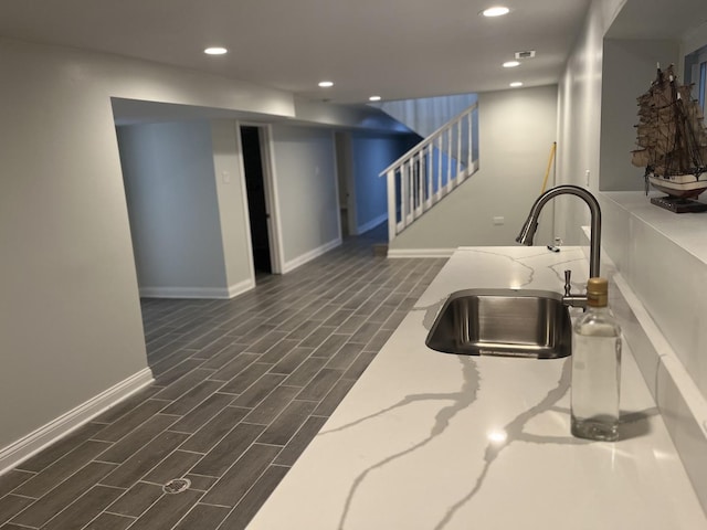 kitchen featuring a sink, recessed lighting, baseboards, wood tiled floor, and light stone countertops