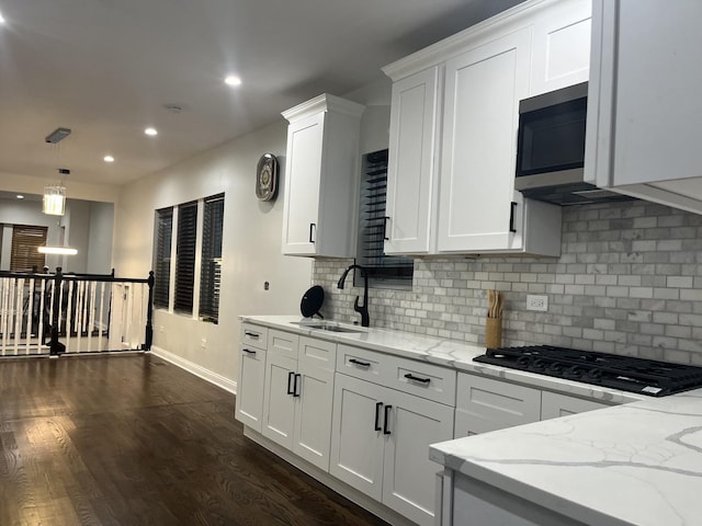 kitchen with dark wood-style flooring, a sink, white cabinets, black gas cooktop, and stainless steel microwave