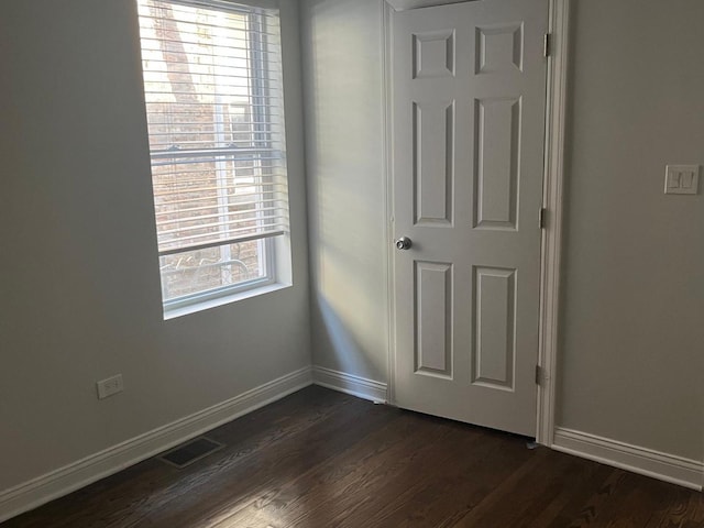 unfurnished bedroom featuring baseboards, visible vents, and dark wood-style flooring